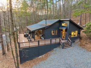 a black cabin in the woods with a deck at Peach and Plumeria Hideaway in Cherry Log