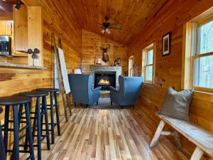 a log cabin living room with a fireplace and stools at The Tree House- Wifi- Firepit- 2 Fireplaces-Garden Tub-Free Activities in Morganton
