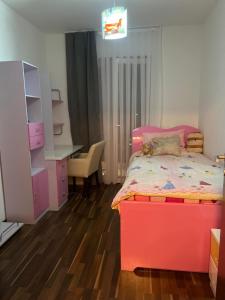 a bedroom with a red bed and a desk and a chair at Apartment center in Ferizaj