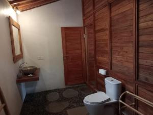a bathroom with a toilet and a wooden door at Loka Amertha in Sidemen