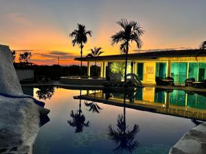 a house with a pool with palm trees and a sunset at Hotel Four20 Zensi - Meta in Lejanías