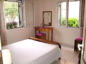 1 dormitorio con cama, mesa y ventanas en Spiridoula apartments en Agios Stefanos