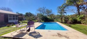 a swimming pool with two chairs and a table in a yard at Mi Casita del Paso in Paso de la Patria