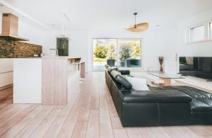 a living room with a black leather couch and a kitchen at Modern 2 Bed with Garden - Bridel in Bridel