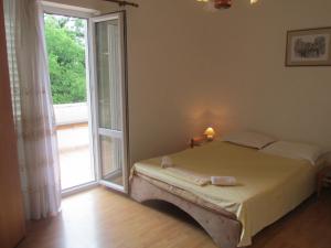 a bedroom with a bed and a large window at Apartmani Kljunak in Zaton