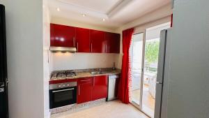 a kitchen with red cabinets and a red curtain at Havre de paix à 100m de la plage in Dar Mohammed Ould Haj Jilali