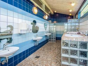 a blue tiled bathroom with two sinks and two mirrors at 4 person holiday home in Hampen in Hampen +34 photos