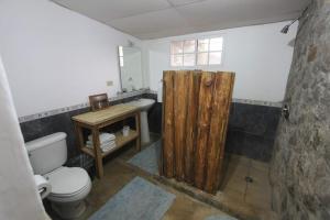 a bathroom with a wooden shower curtain and a toilet at Atlakamani Surf in Chirilagua +16 photos