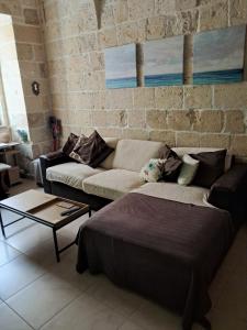 a living room with a couch and a brick wall at Historical Apartment in Bormla in Cospicua