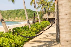 a beach with hammocks and palm trees and the ocean at Casa Lu Hotel Boutique in Mazunte