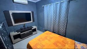 a blue room with a tv and a bed and a table at Casa Aconchegante de Praia in Caraguatatuba