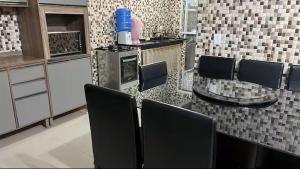 a kitchen with black chairs and a glass table at Casa Aconchegante de Praia in Caraguatatuba