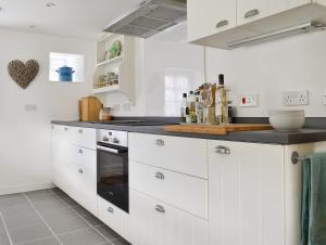 une cuisine avec des armoires blanches et un comptoir noir dans l'établissement Seaton Cottage, à Collieston