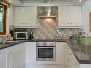 a kitchen with white cabinets and a stove top oven at Pine Lodge in Sewerby