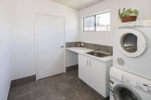 a kitchen with a washing machine and a sink at Beach Bum Bungalow 1- WIFI, Short walk to the beach in Busselton