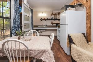 a kitchen and dining room with a table and a refrigerator at Cabin close to FL Caverns! Pool, WI-FI, & Firepit in Marianna +13 photos