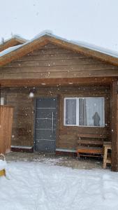 une maison couverte de neige avec un chat à la fenêtre dans l'établissement Samsara, à El Chalten