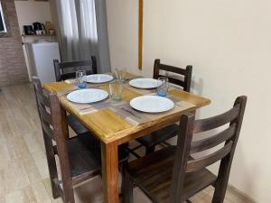 une table en bois avec quatre chaises et des assiettes. dans l'établissement Samsara, à El Chalten