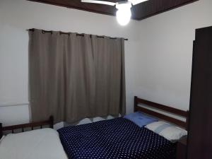 a bedroom with a bed and a window with a curtain at Casa de praia in Itanhaém
