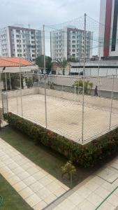 a tennis court behind a fence with flowers at Apt Luar do Sertao in Aracaju