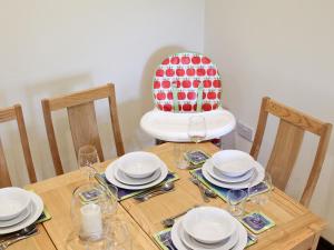 einen Holztisch mit Tellern, Gläsern und einem Stuhl in der Unterkunft Swallow Cottage in Shanklin