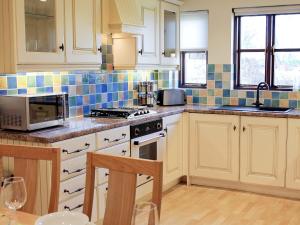 eine Küche mit weißen Schränken und blauen Wandfliesen in der Unterkunft Swallow Cottage in Shanklin