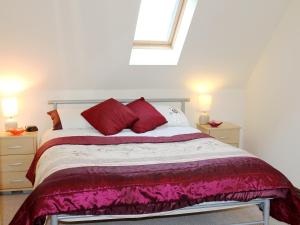 ein Schlafzimmer mit einem großen Bett mit roten Kissen in der Unterkunft Swallow Cottage in Shanklin