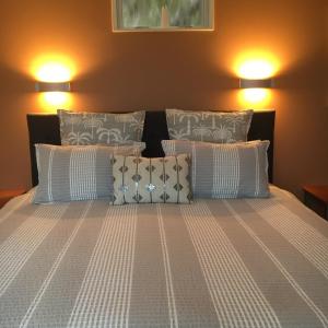 a bed with two lights on top of it at Nikau Apartments Waiheke Island in Onetangi