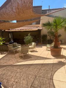 un patio con sedie e palme e un edificio di Les Reflets dAngele Terrasse XXL a Sete a Sète