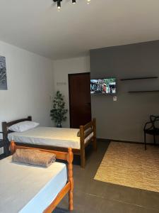 a room with two beds and a tv on the wall at Pousada Central Araquari in Araquari