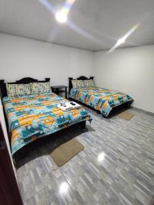 a bedroom with two beds in a room at Hotel La Terraza Raquireña in Ráquira