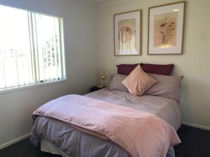 a bedroom with a bed with pink sheets and a window at Fitzroy Holiday Home ideal for Groups and Families in New Plymouth