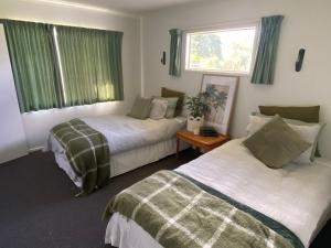 a bedroom with two beds and a window with green curtains at Fitzroy Holiday Home ideal for Groups and Families in New Plymouth
