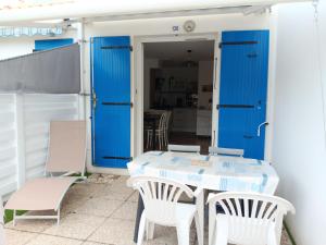 a table and chairs on a patio with blue doors at Maisonnette 4 pers, proche plage et commerces, parking - FR-1-476-247 in La Faute-sur-Mer +3 photos
