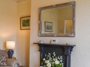 uno specchio sopra un camino in una stanza d'albergo di Waterside Cottage a Saltash
