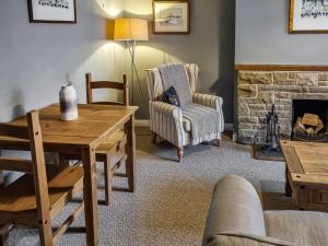 ein Wohnzimmer mit Kamin, Tisch und Stühlen in der Unterkunft Half Moon Cottage in Brafferton