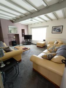 a living room with couches and a flat screen tv at Three Bedroom Countryside Cottage in Darley