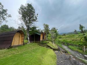 a small building on a hill next to a field at Tranquil Riverside Camping in Ambengan +35 photos