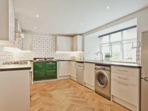a kitchen with white cabinets and a green dishwasher at The Barn in Carnforth