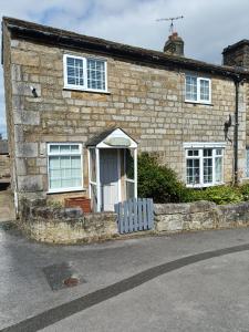 a stone house with a white door on a street at Three Bedroom Countryside Cottage in Darley