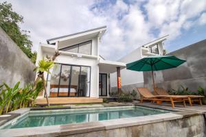 a house with a swimming pool and an umbrella at Umanisa Villas in Gianyar