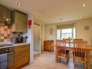 a kitchen with a table and chairs and a microwave at Muirmailing Cottage in Plean