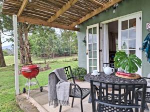 a patio with a table and chairs and a grill at Kamberg Cottages in Mooiriver