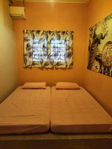 two beds in a small room with a window at Homestay LubokSawah in Pekan Nanas