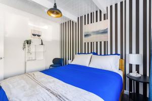 a bedroom with a blue bed and a striped wall at Chic Abode In Central Berkley in Berkeley +68 photos