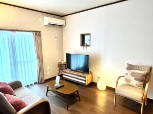 a living room with a couch and a flat screen tv at かみくまハウス in Kumamoto