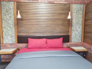 a bed with pink pillows in a room at Ingsala by CafeAtLuv22 in Ban Bo Rae