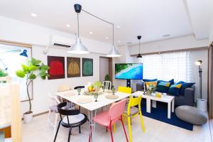 a dining room with a white table and colorful chairs at ゲストハウスsimasima西宝町301 in Takamatsu