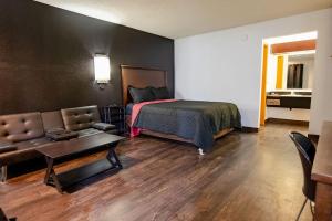 a bedroom with a bed and a couch and a table at Rose City Inn & Suites in Oak Grove
