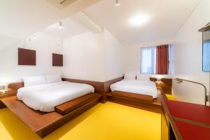 two beds in a room with a yellow rug at Small House Big Door Myeongdong in Seoul